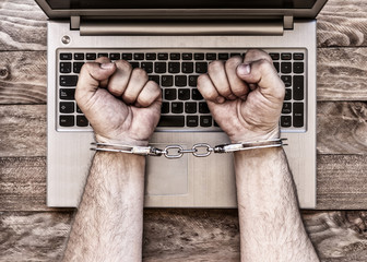 person in handcuffs over computer keyboard